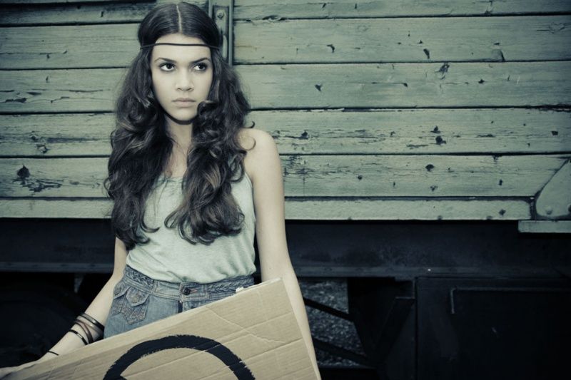 Model mit langen Locken und Stirnband vor einem alten Güterwaggon, Hippie-Look