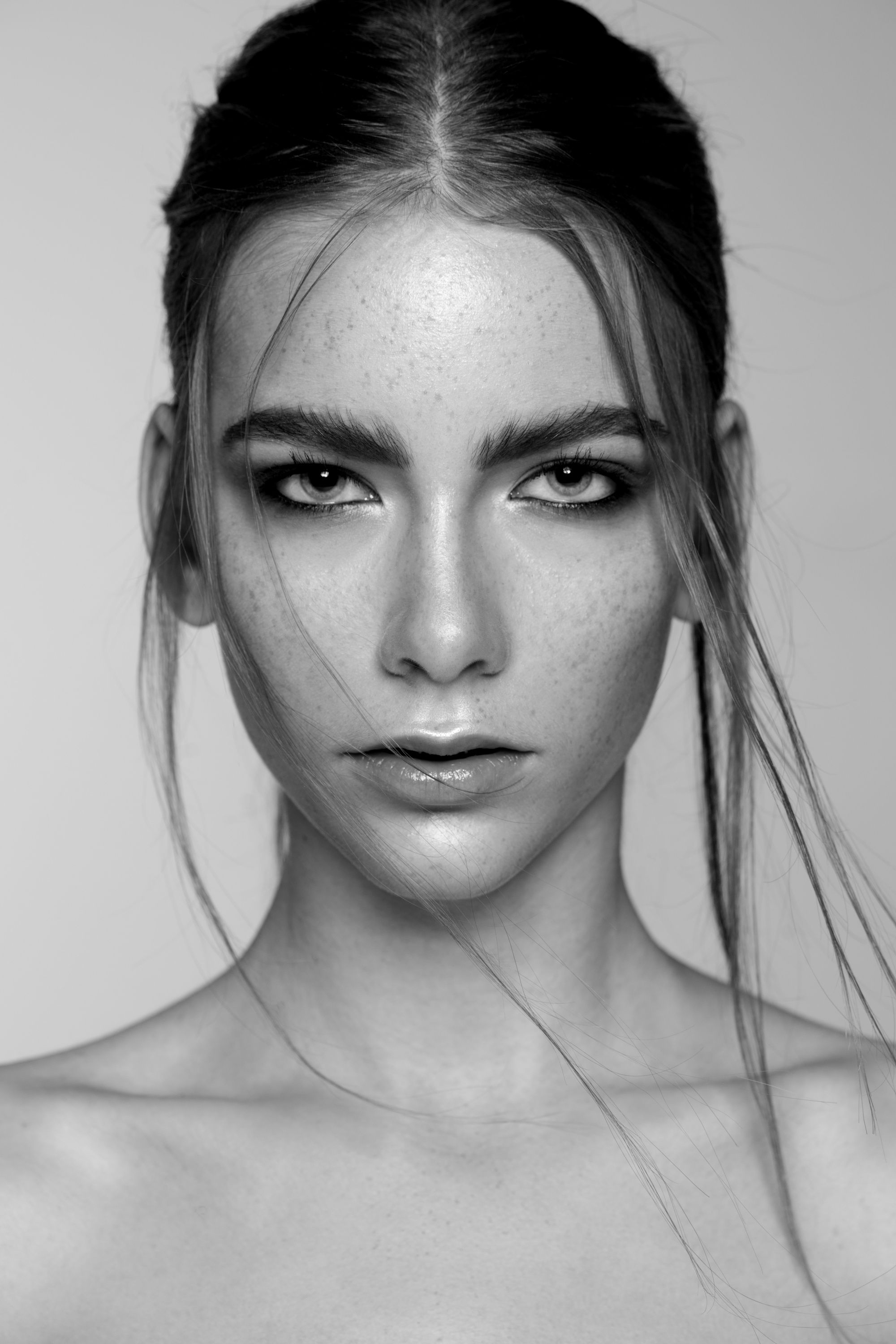 Schwarz-Weiß-Beautyporträt eines Models mit dunklem Augen-Make-up und Wet-Look-Strähnen