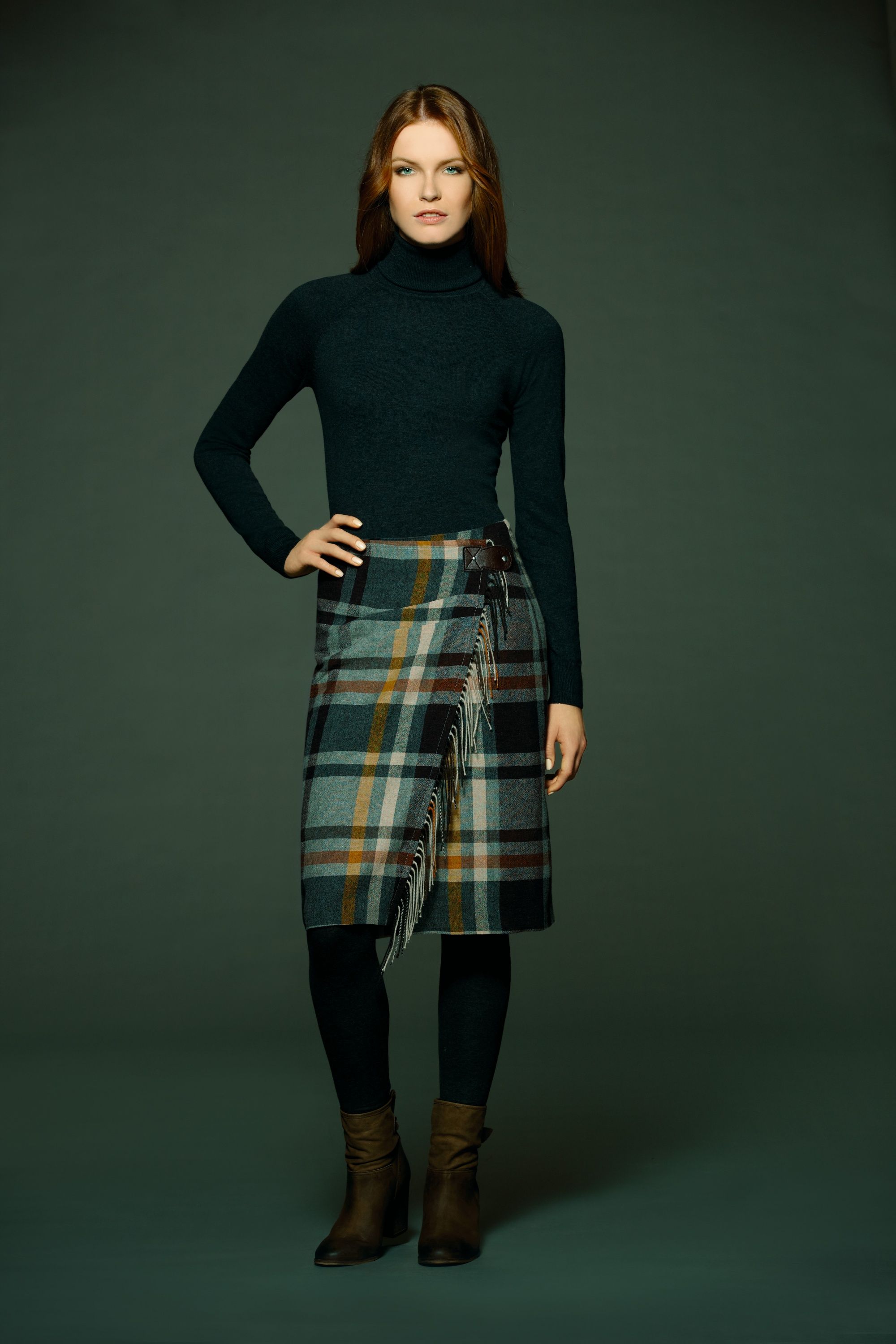 Model im schwarzen Pullover und Karo-Wickelrock mit Hand an der Hüfte, Hirsch Rock
