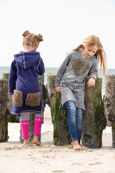 Zwei Mädchen klettern auf Holzpfählen am Strand