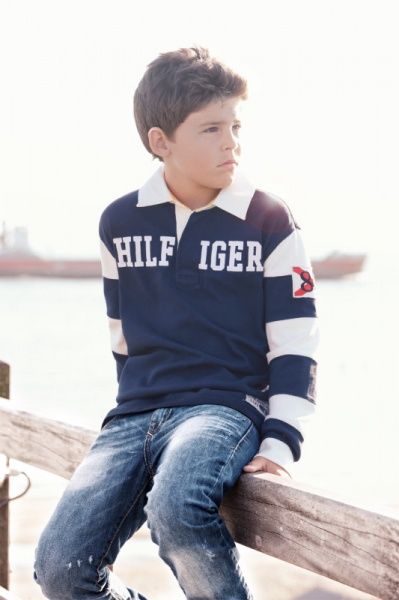 Junge im Tommy-Hilfiger-Rugbyshirt auf einem Holzzaun am Meer